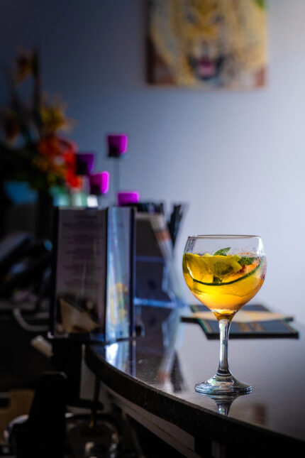A refreshing signature gin cocktail garnished with cucumber on a polished bar top.