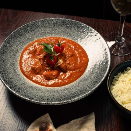 Rich red Hyderabadi curry garnished with tomatoes at Zari Restaurant in Crawley.