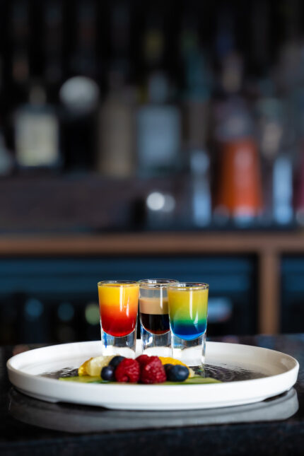 A festive platter of colorful layered dessert shots and fresh berries at Zari Crawley.
