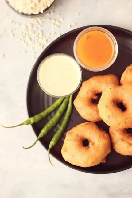 Crispy South Indian medu vada with dipping chutneys and green chillies at Zari Crawley.