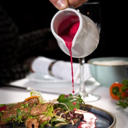 Vibrant pink sauce poured over a gourmet kebab appetizer at Zari Restaurant in Crawley.